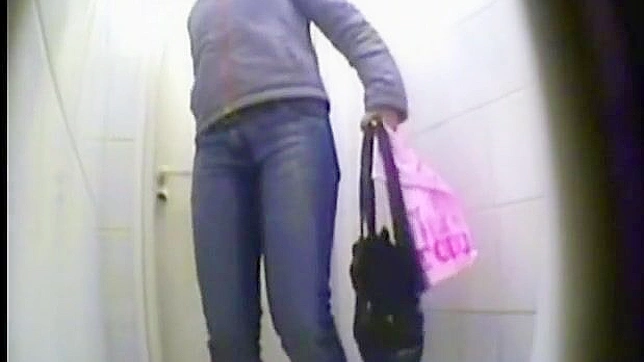 Adorable babe in jeans is ing in the public toilet