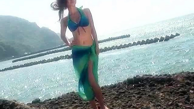 赤毛の従順なアジア人モデルがビーチでポーズをとっている。